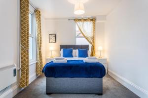 a bedroom with a blue bed and two windows at West Street Studio Apartments in Southend in Southend-on-Sea