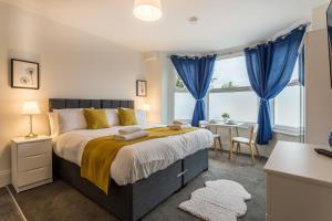 a bedroom with a large bed with blue curtains at West Street Studio Apartments in Southend in Southend-on-Sea