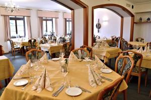 a dining room with tables with yellow tablecloths at Rosenhotel Scherer in Schiffweiler