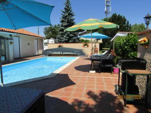a swimming pool with an umbrella and chairs and a table at Galinat in Culmont
