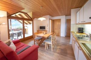 a kitchen and living room with a red couch and a table at Marolhof in Cornaiano