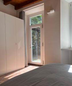 1 dormitorio con una puerta que conduce a una ventana en LA VOLTA - ANTESITUM - historic, on the lake, en Malgrate