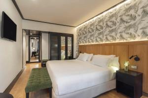 a bedroom with a large white bed and a television at H10 Puerta de Alcalá in Madrid