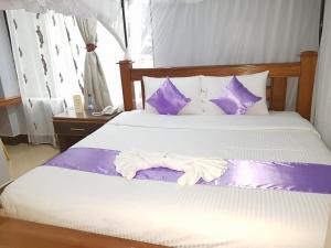 una camera con letto e lenzuola viola e bianche di The Cannas Hotel Suites a Kisii