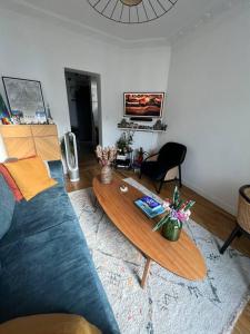 een woonkamer met een blauwe bank en een houten tafel bij Charme et confort à 10 minutes du centre de Paris in Courbevoie