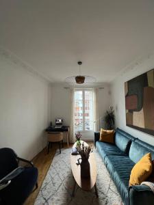 een woonkamer met een blauwe bank en een tafel bij Charme et confort à 10 minutes du centre de Paris in Courbevoie