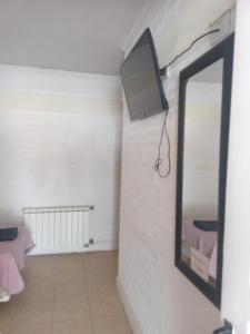 Habitación con espejo y TV en la pared. en hotel el retorno en Catriel