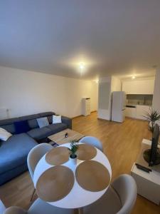 een woonkamer met een blauwe bank en een tafel en stoelen bij Appartement JO, proche Paris in Guyancourt