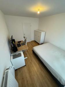1 dormitorio con cama, escritorio y mesa en Appartement JO, proche Paris, en Guyancourt