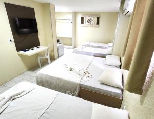 a hotel room with four beds and a television at Guarany Hotel Express in João Pessoa