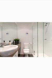 a bathroom with a sink and a toilet and a shower at Bright City Views Melbourne Central Penthouse on Collins in Melbourne