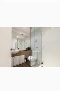 La salle de bains est pourvue de toilettes, d'un lavabo et d'un miroir. dans l'établissement Bright City Views Melbourne Central Penthouse on Collins, à Melbourne