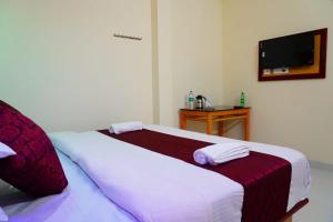 a bedroom with a bed with white sheets and a tv at Angel Holidays in Munnar