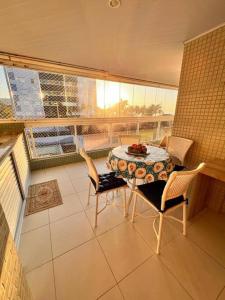 a room with a table and chairs on a balcony at Apartamento pé na areia em Bertioga. in Bertioga +12 photos