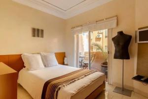 um quarto de hotel com uma cama e uma varanda em Joli appartement centre Gueliz em Marrakech