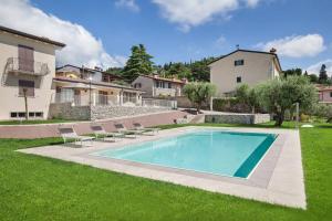 een zwembad in een tuin met stoelen en een huis bij Villa Chiara APT 2-Appartamento in villa con piscina in Cavaion Veronese