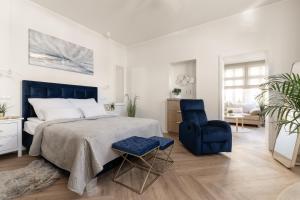 - une chambre avec un grand lit et une chaise bleue dans l'établissement Sanhaus Apartments - Apartamenty Koral z parkingiem - 200 m od plaży, à Sopot