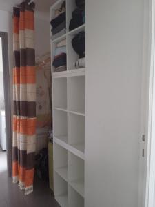 a closet with white shelves and an orange and black curtain at Les capucines in Saint-Brieuc +2 photos