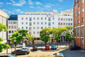 a large white building with cars parked in a parking lot at CityClass Hotel am Dom in Cologne