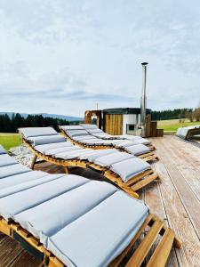 a row of white lounges on a wooden deck at Farma Náhlov in Frymburk