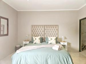 a white bedroom with a large bed with two tables at Bosveld In Die Stad Guesthouse in Alberton