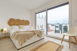 Dormitorio blanco con cama y ventana grande en Inspiration Villa en Ribamar