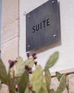 a sign that reads suite on a wall with a plant at Vicoloterzo Suite in Bari