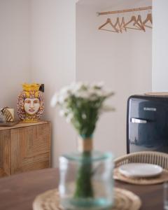 eine Vase mit Blumen auf einem Tisch vor einem Fernseher in der Unterkunft Vicoloterzo Suite in Bari