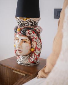 Eine Vase mit einem Gesicht auf dem Tisch in der Unterkunft Vicoloterzo Suite in Bari