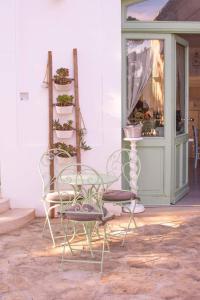 two chairs and a table and a shelf with plants at Masseria Fabula Bistrot & Maison in Monopoli