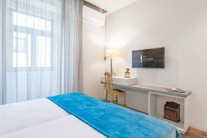 a bedroom with a bed and a desk with a television at GuestReady - Jardim das Oliveiras GuestHouse in Porto