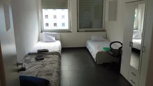 um pequeno quarto com duas camas e duas janelas em Viva Zimmer in Heilbronn Zentrum em Heilbronn