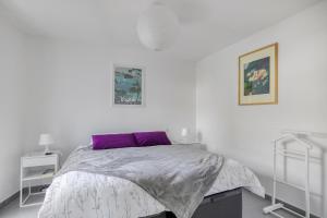 a white bedroom with a bed with a purple pillow at Nouvelle Ère - Appt à moins d’un km de la plage in Le Lavandou