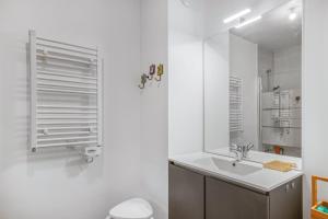 a white bathroom with a sink and a mirror at Nouvelle Ère - Appt à moins d’un km de la plage in Le Lavandou +7 photos