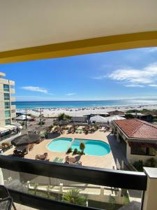 a view of the beach from the balcony of a resort at Varandas ao mar loft 302 Praia Grande in Arraial do Cabo