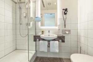 a bathroom with a sink and a shower at CityClass Hotel am Dom in Cologne