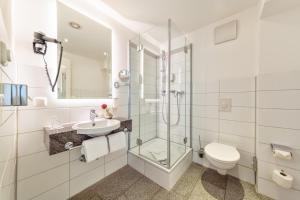 a bathroom with a shower toilet and a sink at CityClass Hotel am Dom in Cologne