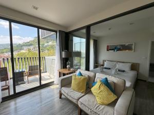 a bedroom with a bed and a couch and a balcony at The Deck Condominium by Lofty in Patong Beach