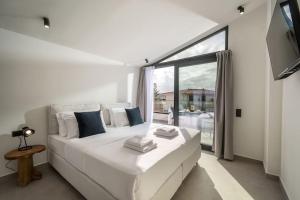 a white bed in a room with a large window at Destino Grand Villa Private Pool in Gournes +32 photos