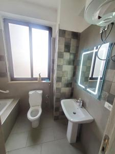 a bathroom with a toilet and a sink and a window at YOLE Furnished Apartments in Addis Ababa