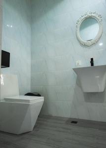 a white bathroom with a toilet and a mirror at CMP APARTMENTS in Kasoa