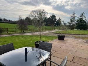 a table and chairs with a tree on a patio at Yew Tree Bungalow, Onneley, Cheshire in Crewe