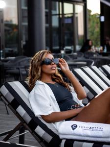 uma mulher sentada numa cadeira de praia com óculos de sol em The Capital Mbombela em Nelspruit