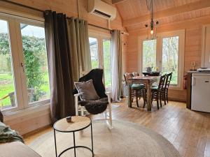 ein Wohnzimmer mit einem Tisch, Stühlen und Fenstern in der Unterkunft Vakantiewoning midden in de natuur GR02 Grijpskerke in Grijpskerke