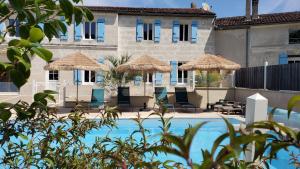 a resort with a swimming pool with straw umbrellas at Les Cuves - Saintes in Chaniers