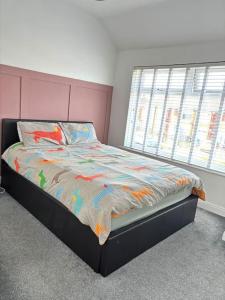 a bedroom with a bed with a colorful comforter and a window at Two bedroom terrace house with parking in Hull