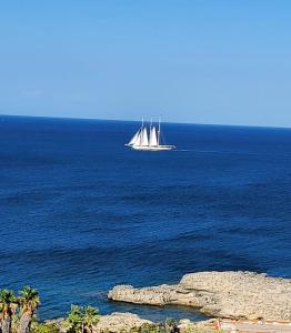 a boat in the ocean with a sail boat at Guest Room Perla Marina in Augusta