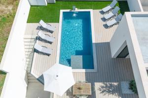 een uitzicht over een zwembad met stoelen en parasols bij Inspiration Villa in Ribamar
