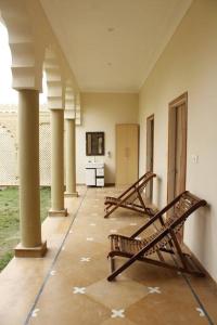 two benches sitting in a room with columns at Farm Aavjo - A Conscious Stay in Pushkar