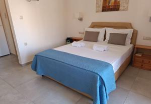a bedroom with a large bed with a blue blanket at Superior Savvas Apartments by the sea in Agia Pelagia
